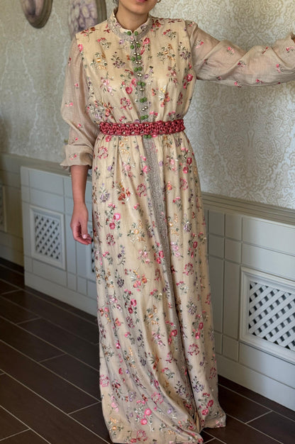 Person wearing a floral dress with a red belt in a room with tiled walls and a vent.