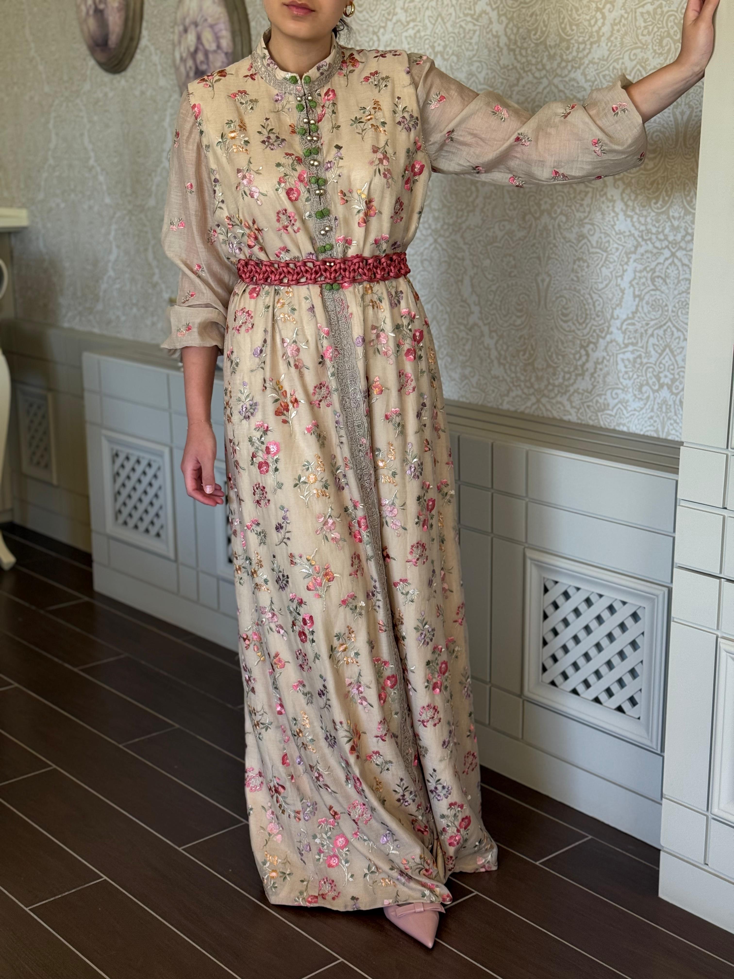 Person wearing a floral dress with a red belt in a tiled room.