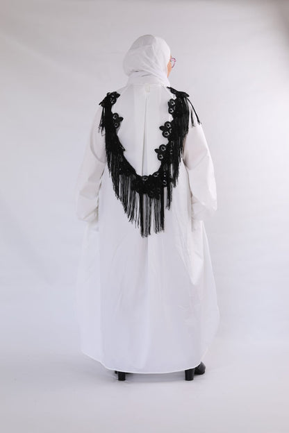 White dress with black floral embroidery and fringe on a white background
