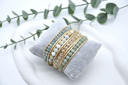 Set of beaded bracelets on a gray cushion with green leaves in the background