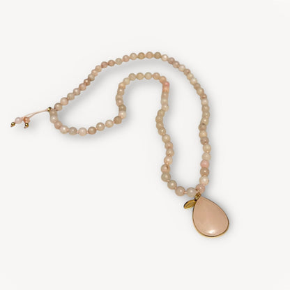 Pearl necklace with a teardrop-shaped pink pendant on a white background