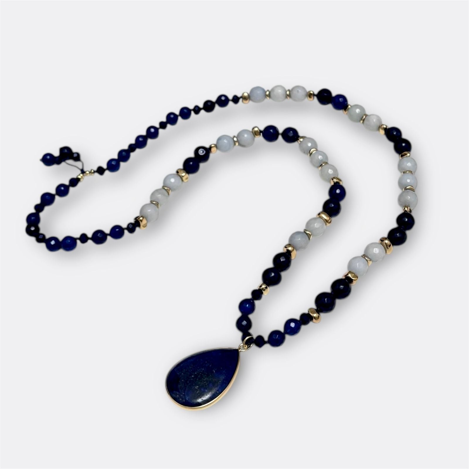 Necklace with blue and white beads and a teardrop pendant on a white background