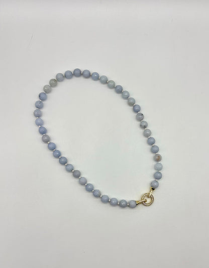 Beaded necklace with a gold clasp on a light gray background
