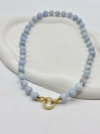 Blue beaded bracelet with a gold clasp on a white background