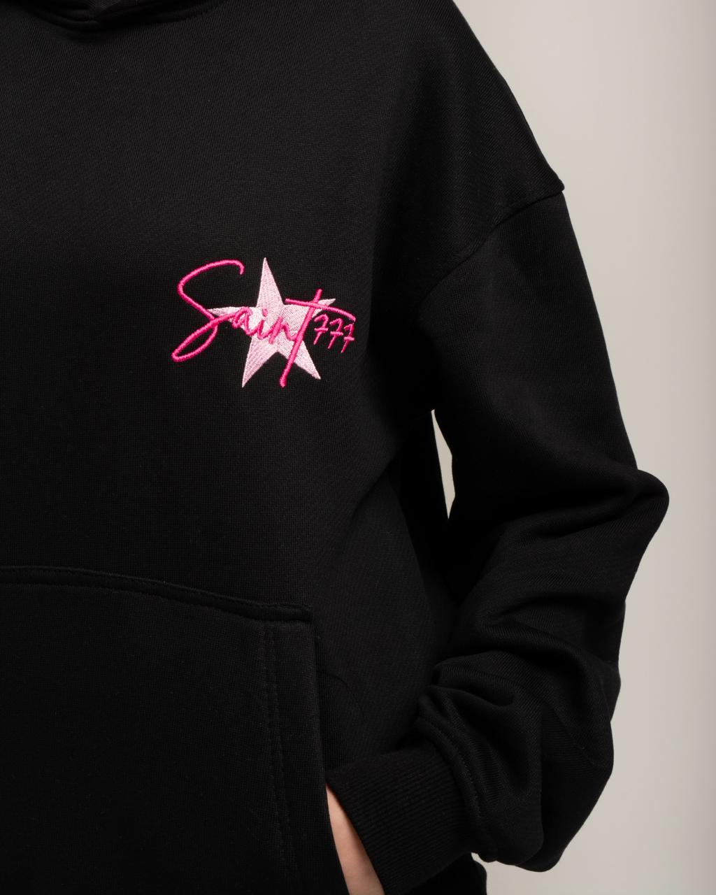 Black hoodie with pink and white logo on a neutral background