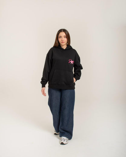 Person wearing a black hoodie with a pink logo on a white background