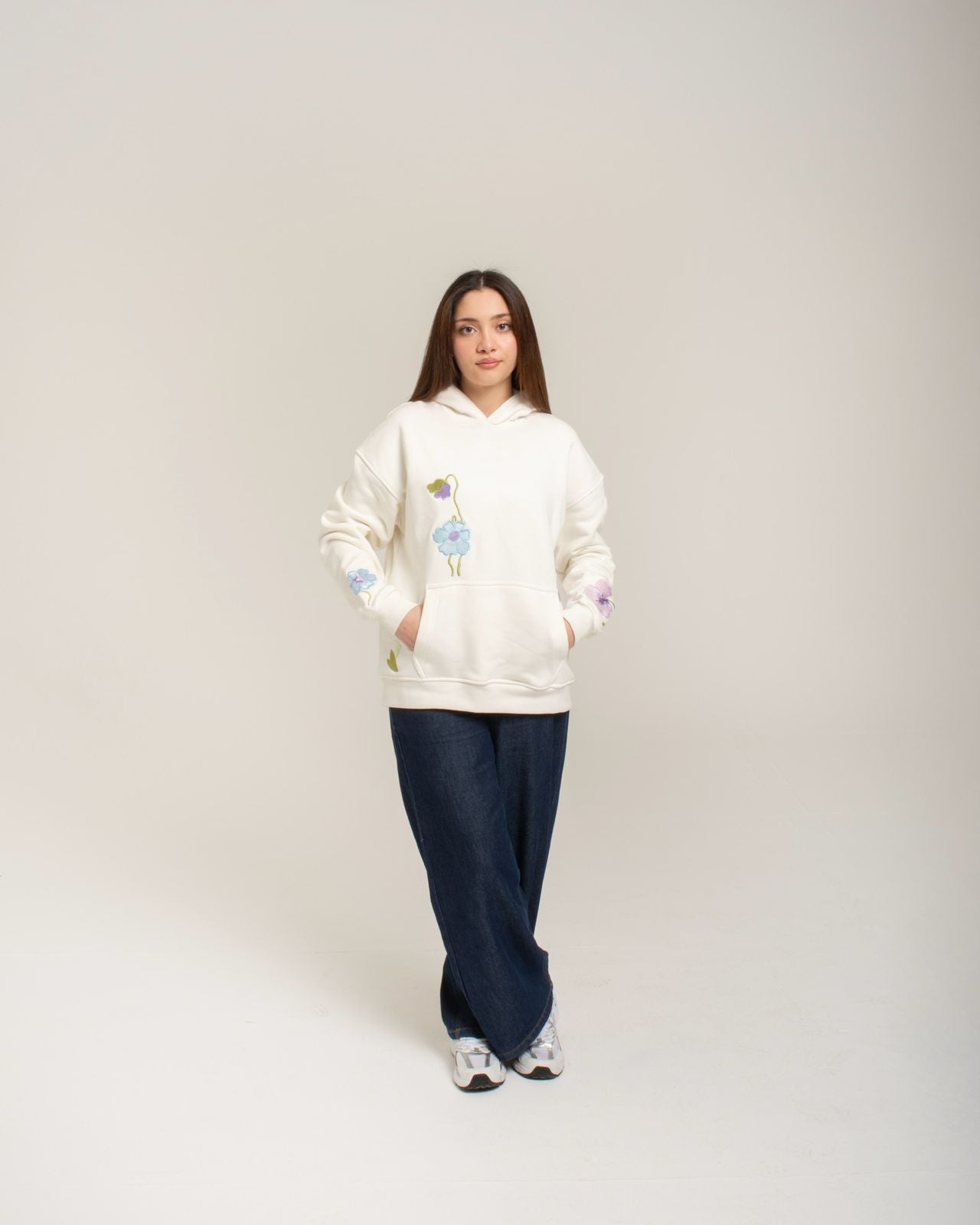 Person wearing a white hoodie with colorful designs on a plain background