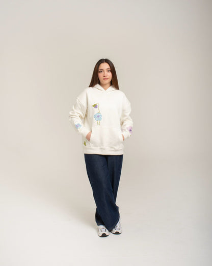 Person wearing a white hoodie with colorful designs on a plain background