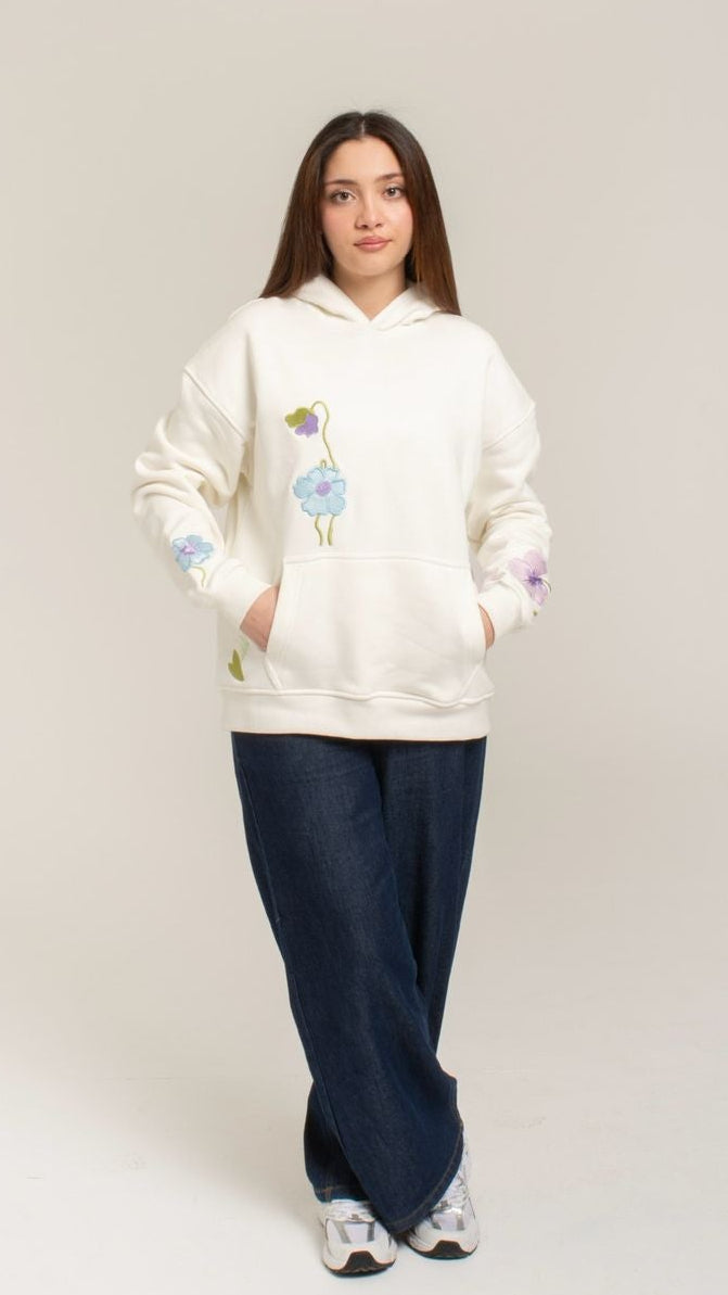 Person wearing a white hoodie with colorful designs on a plain background