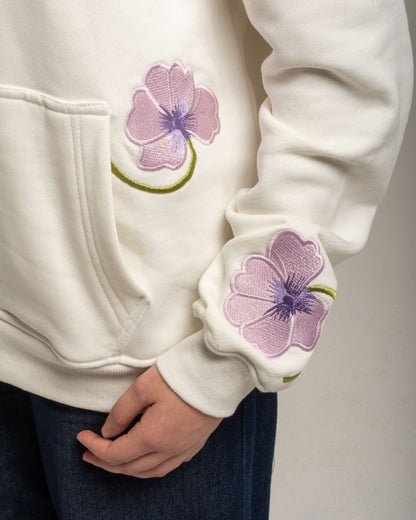 White hoodie with purple floral designs on the sleeves against a gray background