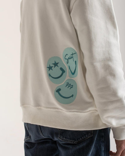 White sweatshirt with blue smiley face design on a plain background