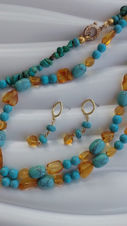 A multi-strand turquoise and amber beaded necklace set with matching drop earrings, displayed on a white wavy surface.