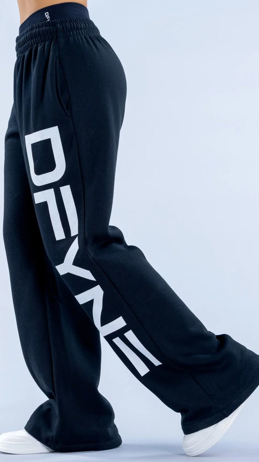 Black sweatpants with 'DEYN' branding on a light blue background