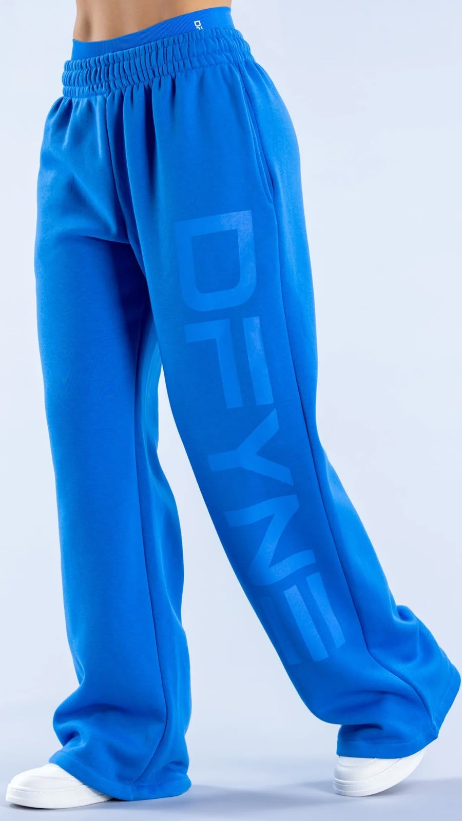 Blue sweatpants with 'DEVA' branding on a light gray background