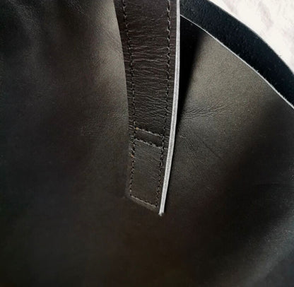 Close-up of a dark black leather bag with visible stitching.