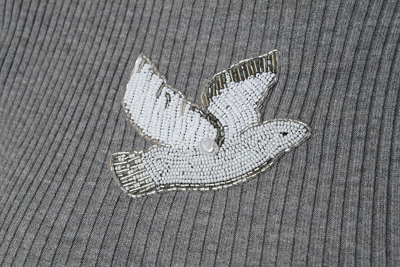 Decorative beaded dove on a textured gray fabric background