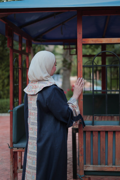 Woman in a hijab standing in front of a wooden structure with a blurred background