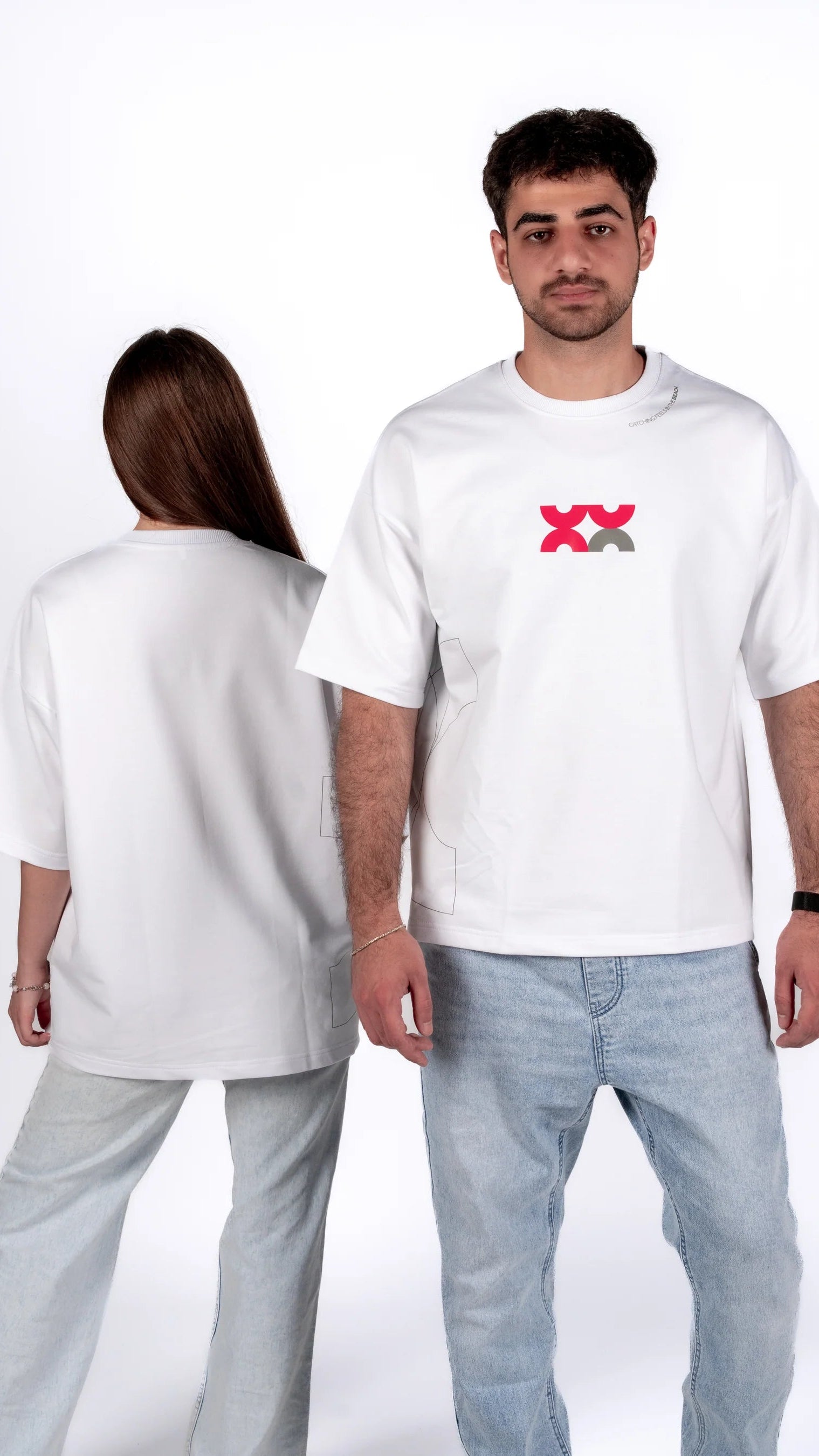 Two people wearing white t-shirts with a logo on a plain background