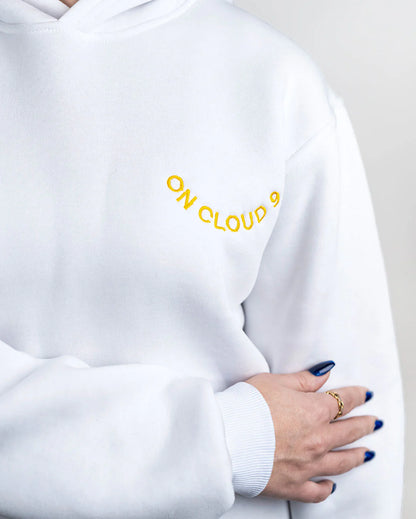 White sweatshirt with 'ON CLOUD 9' text in yellow on a plain background
