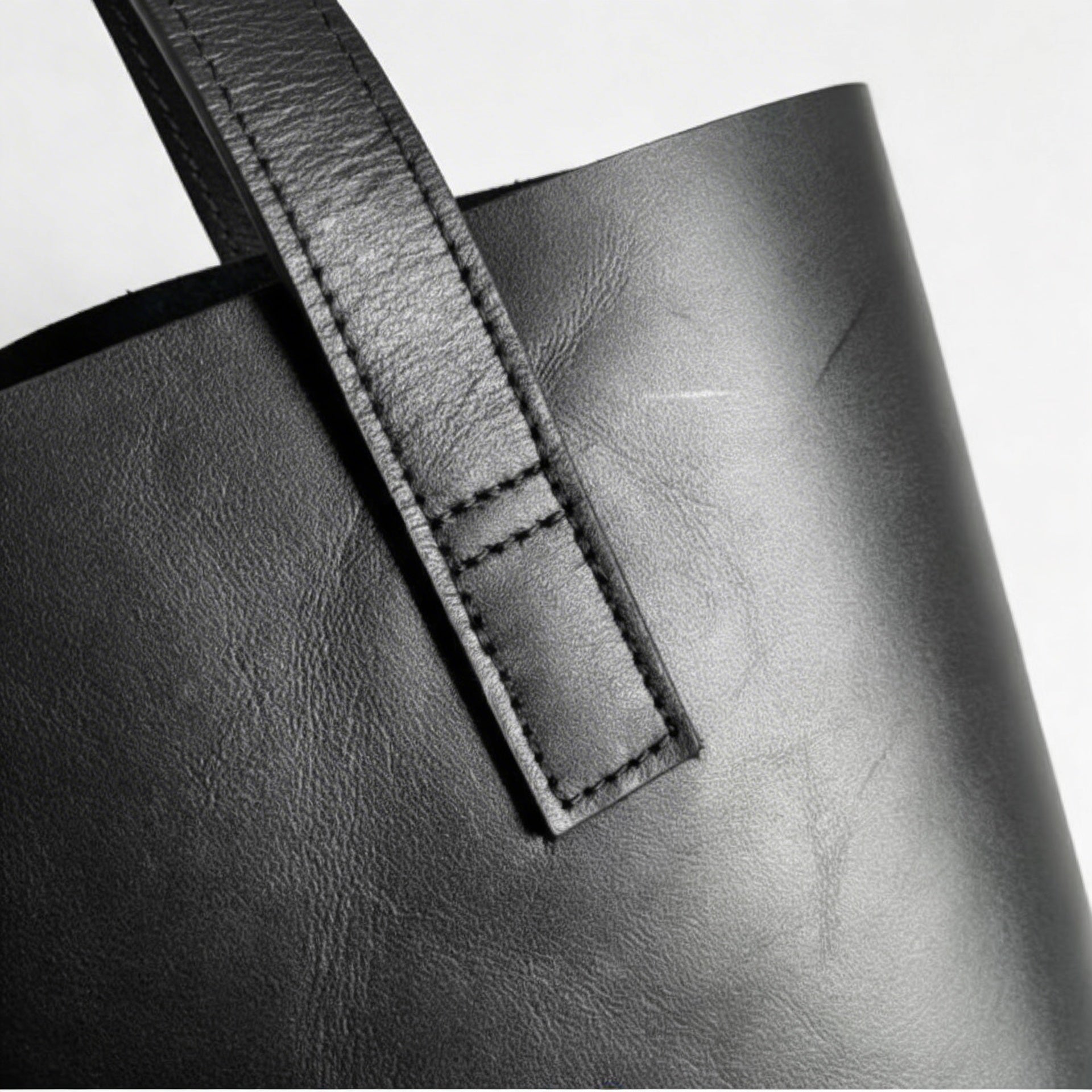 Close-up of a black leather bag with a strap on a white background