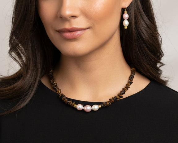 Woman wearing a black top and pearl necklace with a neutral background