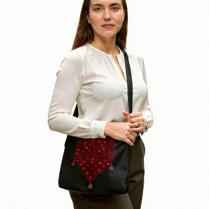 Woman holding a black bag with a red embroidered panel on a white background