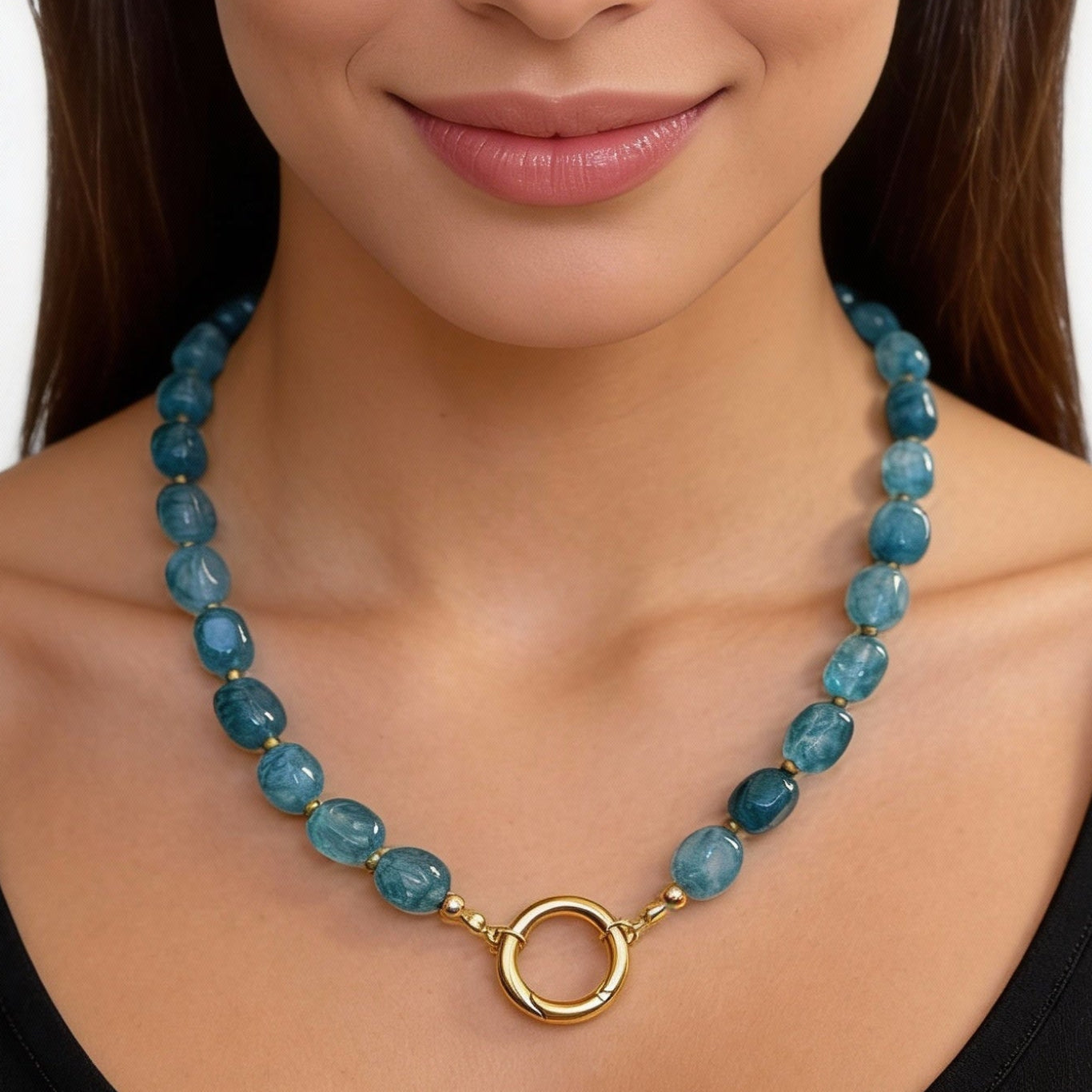 Woman wearing a blue beaded necklace with a gold clasp on a white background