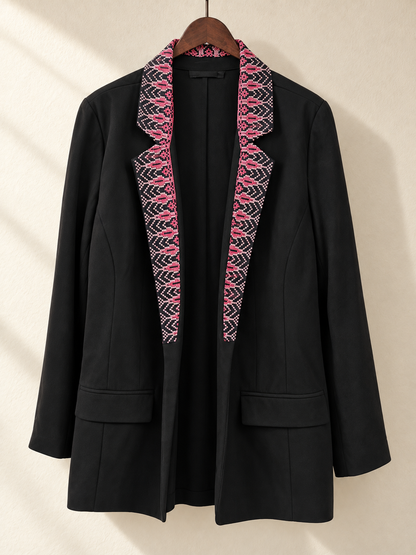 Front view of black blazer with pink embroidered collar and lapels on a wooden hanger